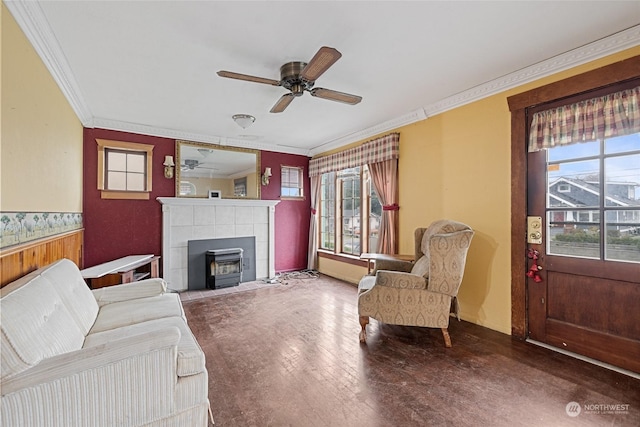 living room featuring wood-type flooring, ornamental molding, a wood stove, and ceiling fan