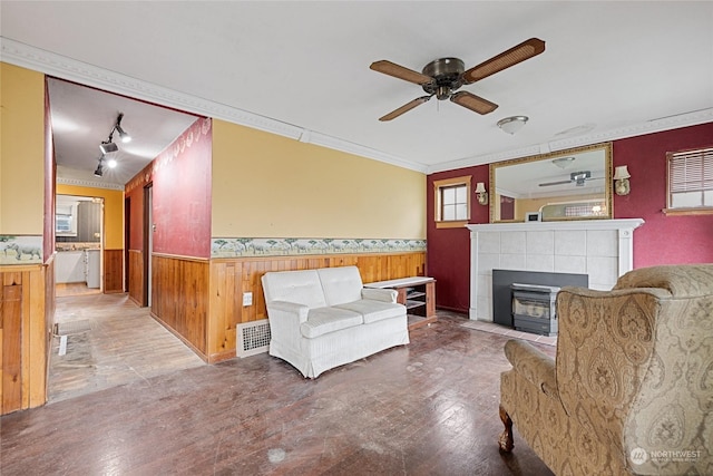 living room with ceiling fan, wooden walls, crown molding, and wood-type flooring