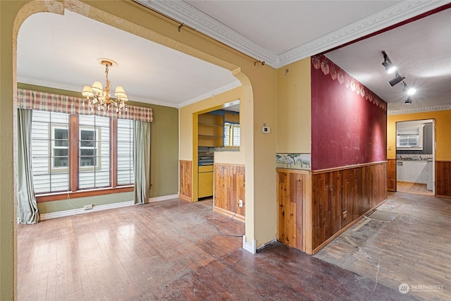 kitchen featuring ornamental molding, dark wood-type flooring, a notable chandelier, and wood walls