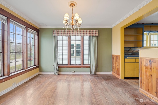 unfurnished dining area with hardwood / wood-style floors, a chandelier, crown molding, and plenty of natural light