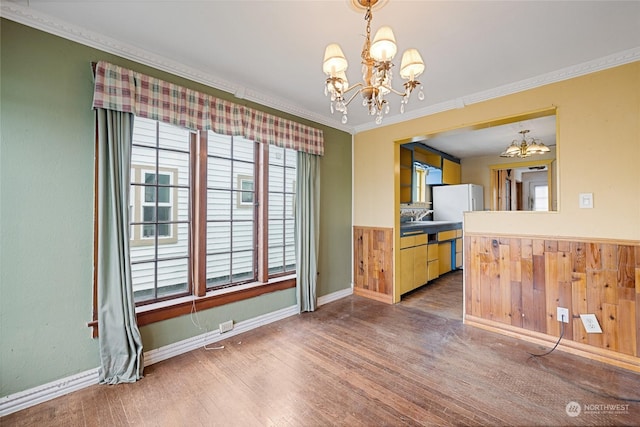 unfurnished dining area with a notable chandelier, ornamental molding, and hardwood / wood-style floors