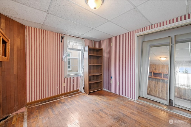 empty room with wood-type flooring and a drop ceiling