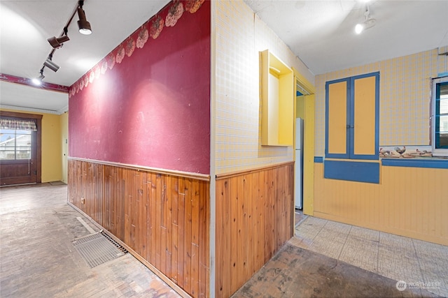 hall featuring rail lighting and wooden walls