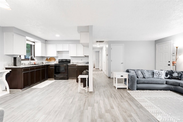 kitchen with light countertops, black electric range oven, open floor plan, white cabinetry, and a sink