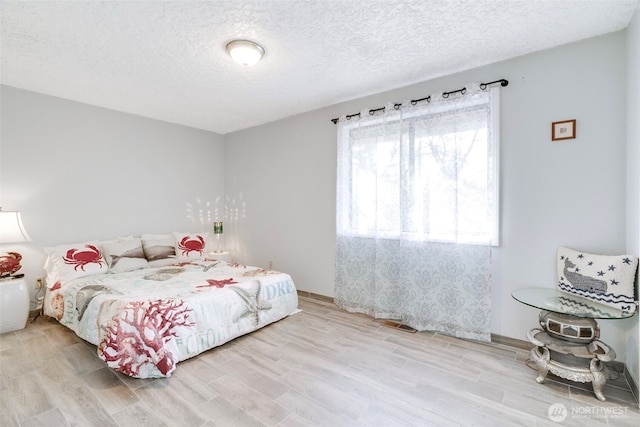 bedroom featuring a textured ceiling and light wood finished floors