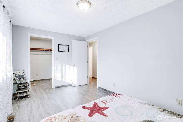 unfurnished bedroom featuring a textured ceiling, light wood finished floors, a closet, and baseboards