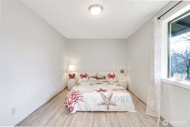 bedroom featuring wood tiled floor, baseboards, and a textured ceiling