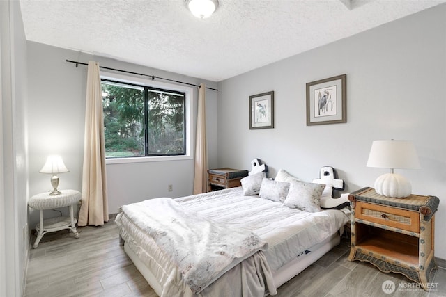 bedroom with a textured ceiling and wood finished floors