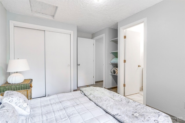 bedroom featuring a textured ceiling, a closet, and attic access