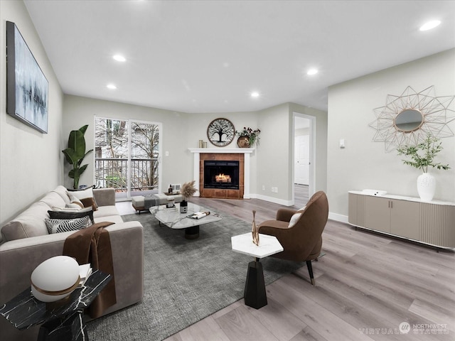 living room featuring a tile fireplace and light hardwood / wood-style flooring