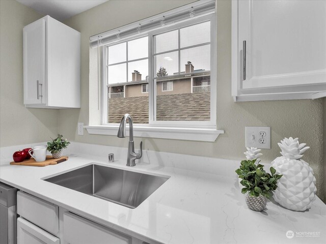 kitchen with sink, white cabinetry, dishwasher, and light stone countertops