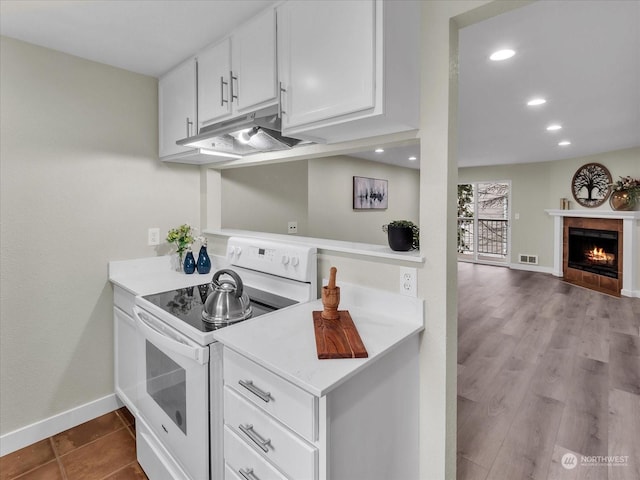 kitchen featuring white cabinets, white range with electric stovetop, and a fireplace