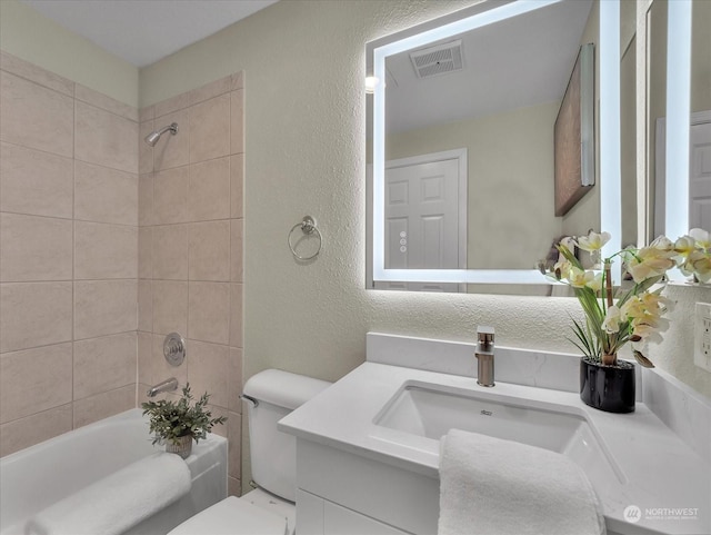 full bathroom featuring toilet, tiled shower / bath, and vanity