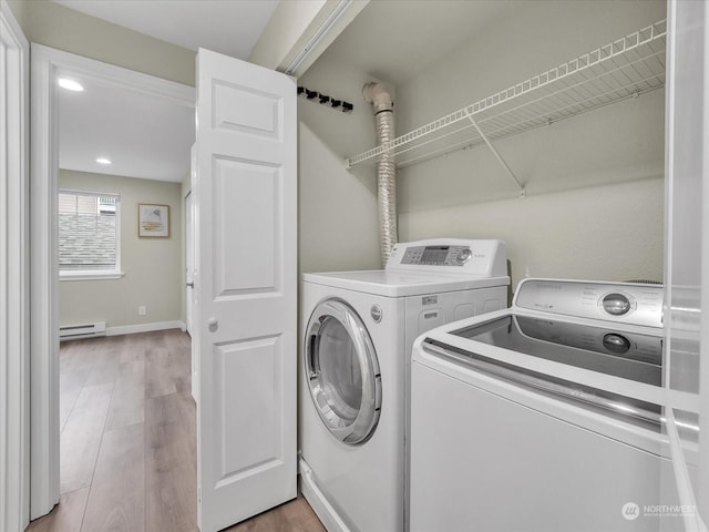 laundry area with washer and dryer, a baseboard heating unit, and light hardwood / wood-style flooring