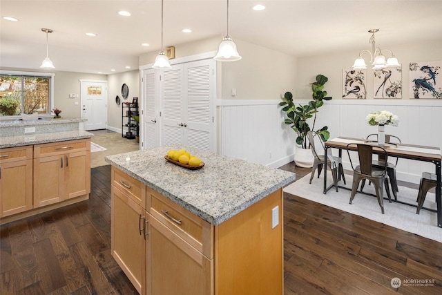 kitchen featuring light stone counters, pendant lighting, dark hardwood / wood-style flooring, and a kitchen island