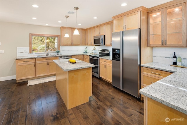 kitchen featuring stainless steel appliances, dark hardwood / wood-style floors, decorative light fixtures, a kitchen island, and light stone counters