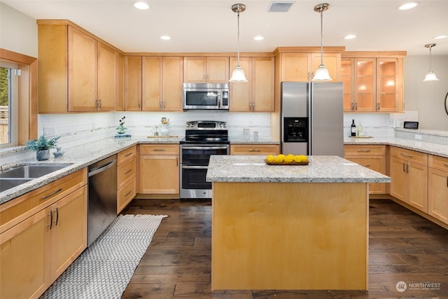 kitchen with light brown cabinetry, dark wood-type flooring, stainless steel appliances, and a kitchen island