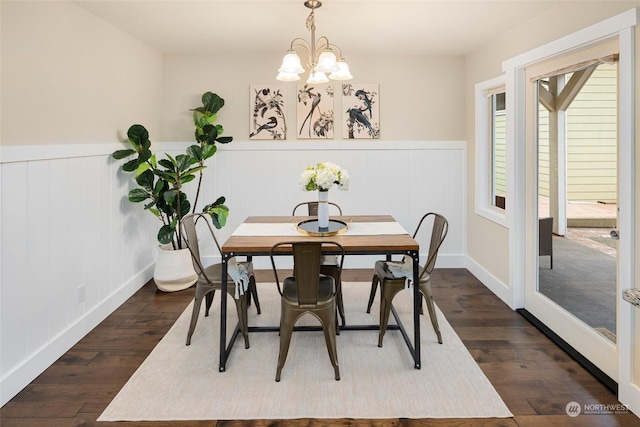 dining space with dark hardwood / wood-style floors and a notable chandelier