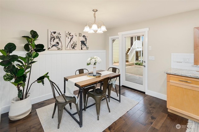 dining space featuring dark wood-type flooring and an inviting chandelier