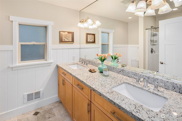 bathroom with toilet, vanity, a notable chandelier, and walk in shower