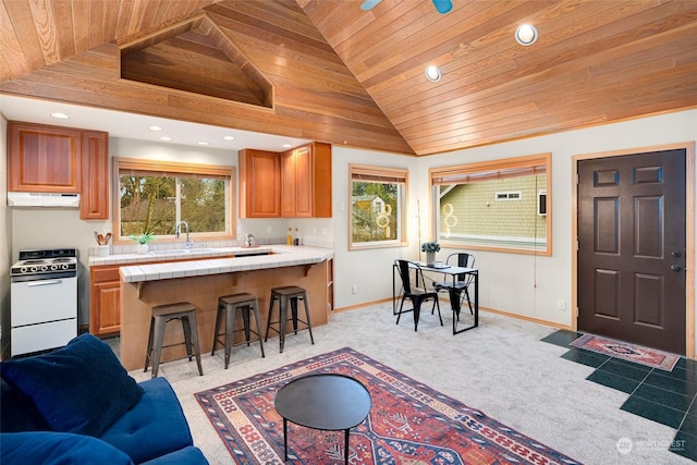 kitchen featuring light carpet, white stove, a breakfast bar, and wooden ceiling