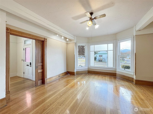 empty room with a textured ceiling, ceiling fan, and light wood-type flooring