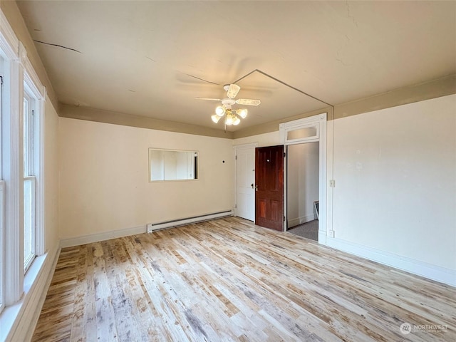 empty room featuring a baseboard heating unit, ceiling fan, and light wood-type flooring