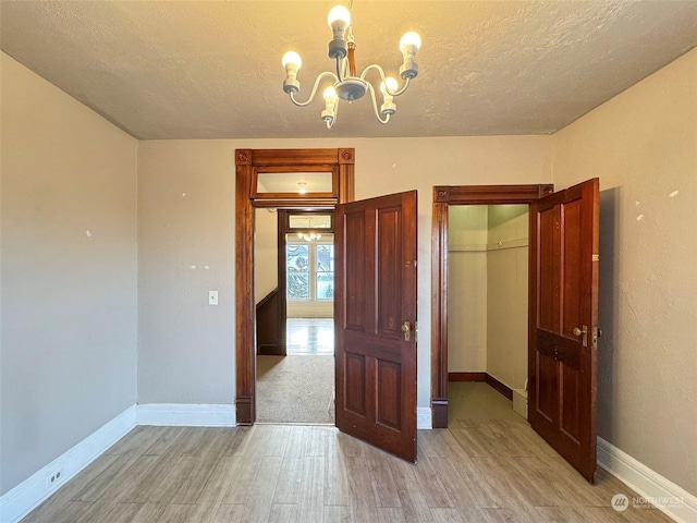 spare room featuring a chandelier, light hardwood / wood-style floors, and a textured ceiling