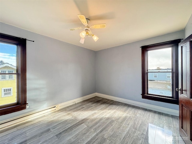 empty room with ceiling fan, light hardwood / wood-style flooring, and a baseboard heating unit