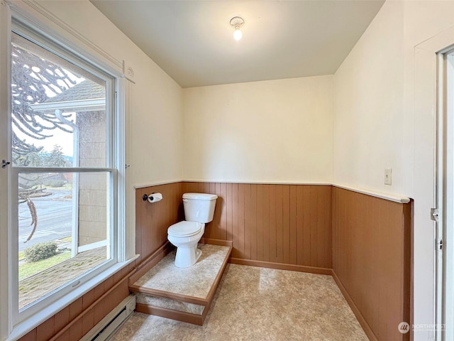 bathroom with wooden walls, a baseboard radiator, and toilet