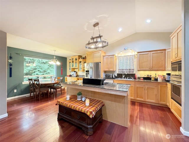 kitchen featuring hanging light fixtures, a center island, light brown cabinets, appliances with stainless steel finishes, and sink