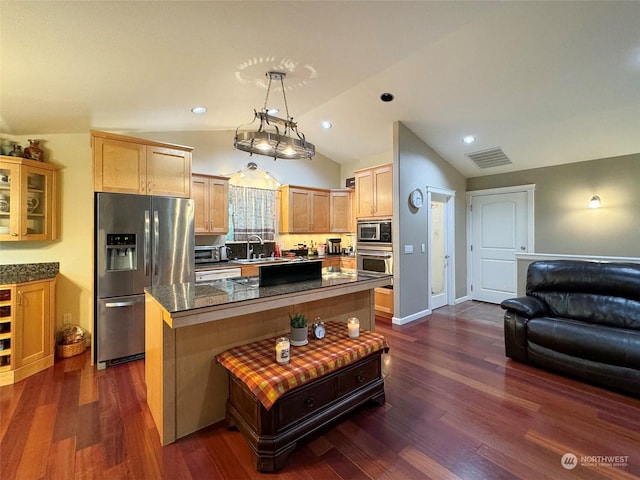 kitchen featuring appliances with stainless steel finishes, pendant lighting, a kitchen island, sink, and lofted ceiling