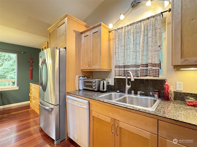 kitchen with sink, dishwasher, light brown cabinetry, stainless steel refrigerator, and dark wood-type flooring