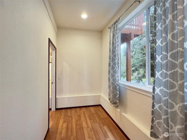 corridor featuring a healthy amount of sunlight and light hardwood / wood-style flooring