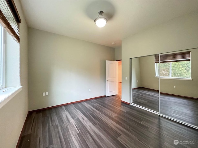 unfurnished bedroom featuring dark wood-type flooring and a closet