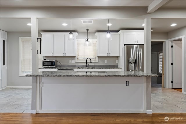 kitchen featuring stainless steel appliances, pendant lighting, dark stone countertops, white cabinets, and a kitchen island