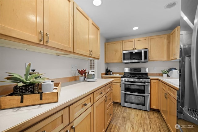 kitchen featuring stainless steel appliances, light wood-type flooring, and light brown cabinetry