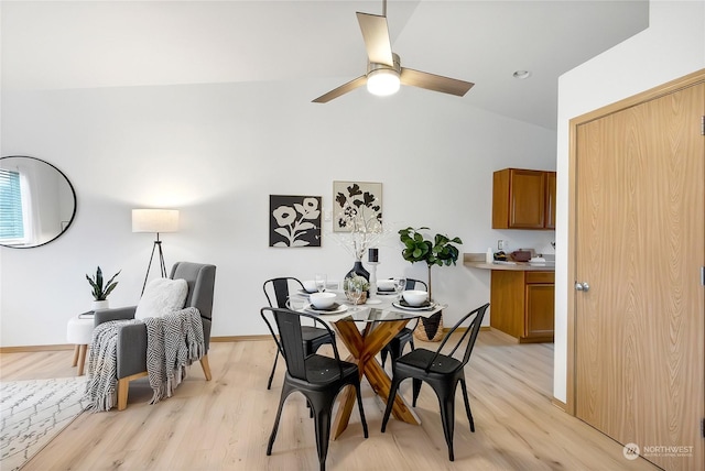 dining space with ceiling fan, vaulted ceiling, and light wood-type flooring