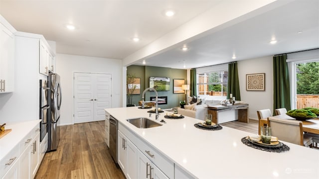 kitchen with sink, white cabinetry, light hardwood / wood-style flooring, dishwasher, and a healthy amount of sunlight