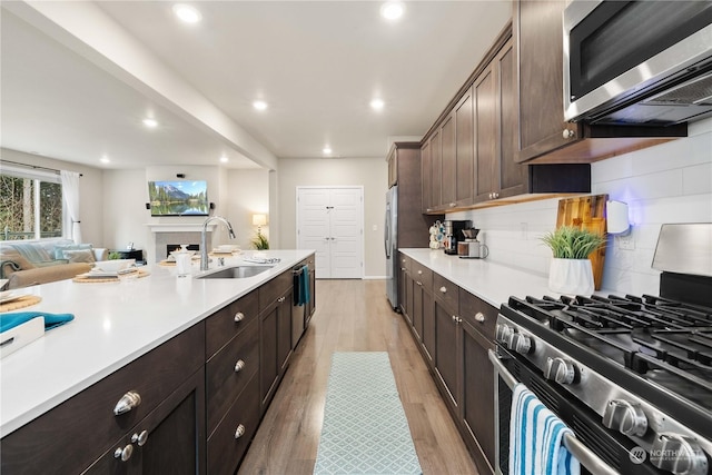 kitchen with appliances with stainless steel finishes, tasteful backsplash, dark brown cabinets, and sink