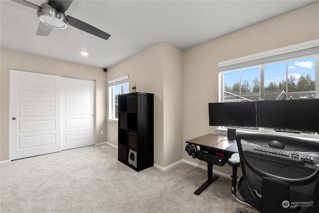 office featuring a healthy amount of sunlight, ceiling fan, and light carpet