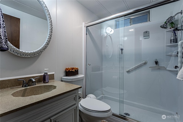 bathroom with toilet, vanity, and a shower with shower door