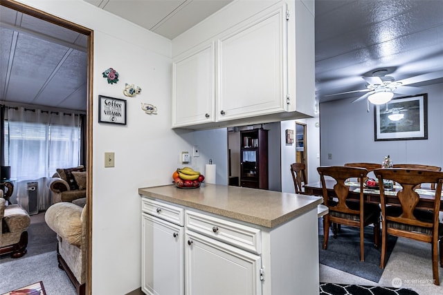 kitchen featuring light carpet, ceiling fan, and white cabinets