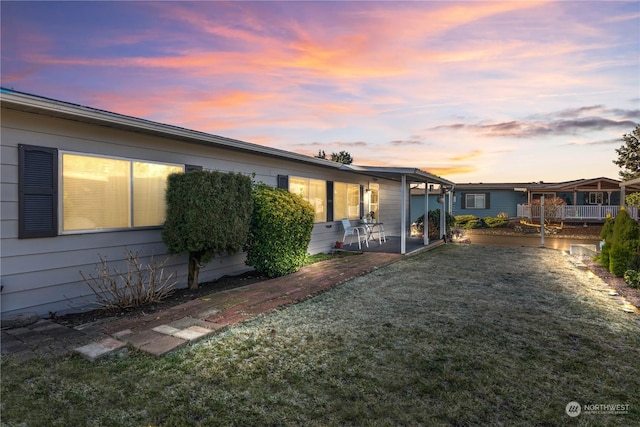 property exterior at dusk featuring a patio and a lawn