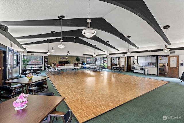 interior space featuring pendant lighting, vaulted ceiling with beams, and a textured ceiling