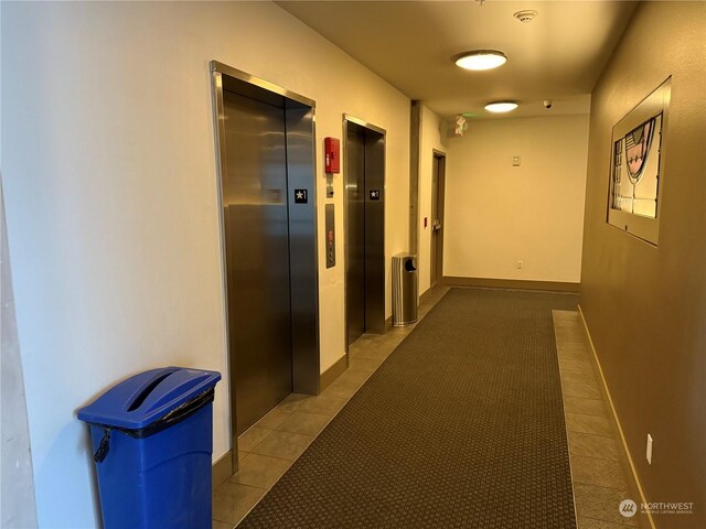 hallway featuring elevator and light tile patterned flooring