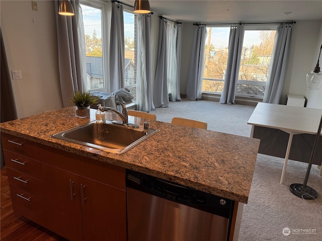 kitchen with stainless steel dishwasher, sink, plenty of natural light, and an island with sink