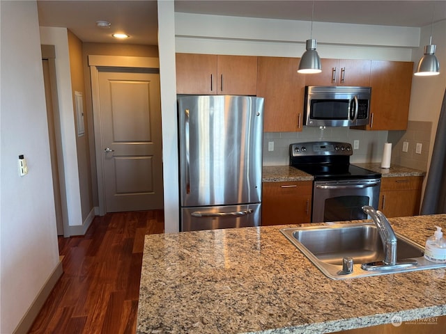 kitchen featuring stainless steel appliances, backsplash, pendant lighting, and sink