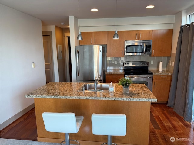 kitchen featuring appliances with stainless steel finishes, pendant lighting, decorative backsplash, and a kitchen breakfast bar