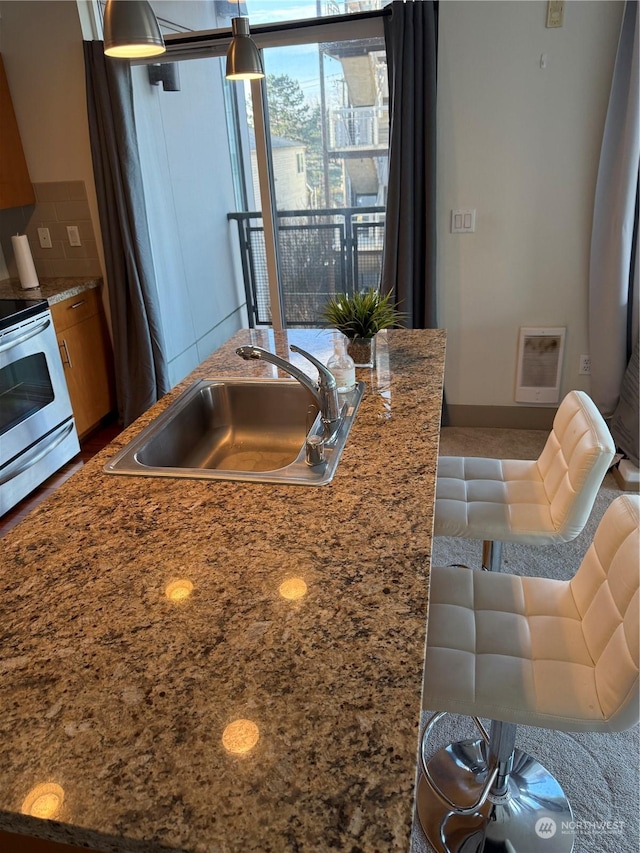 kitchen featuring sink, decorative light fixtures, electric stove, and backsplash